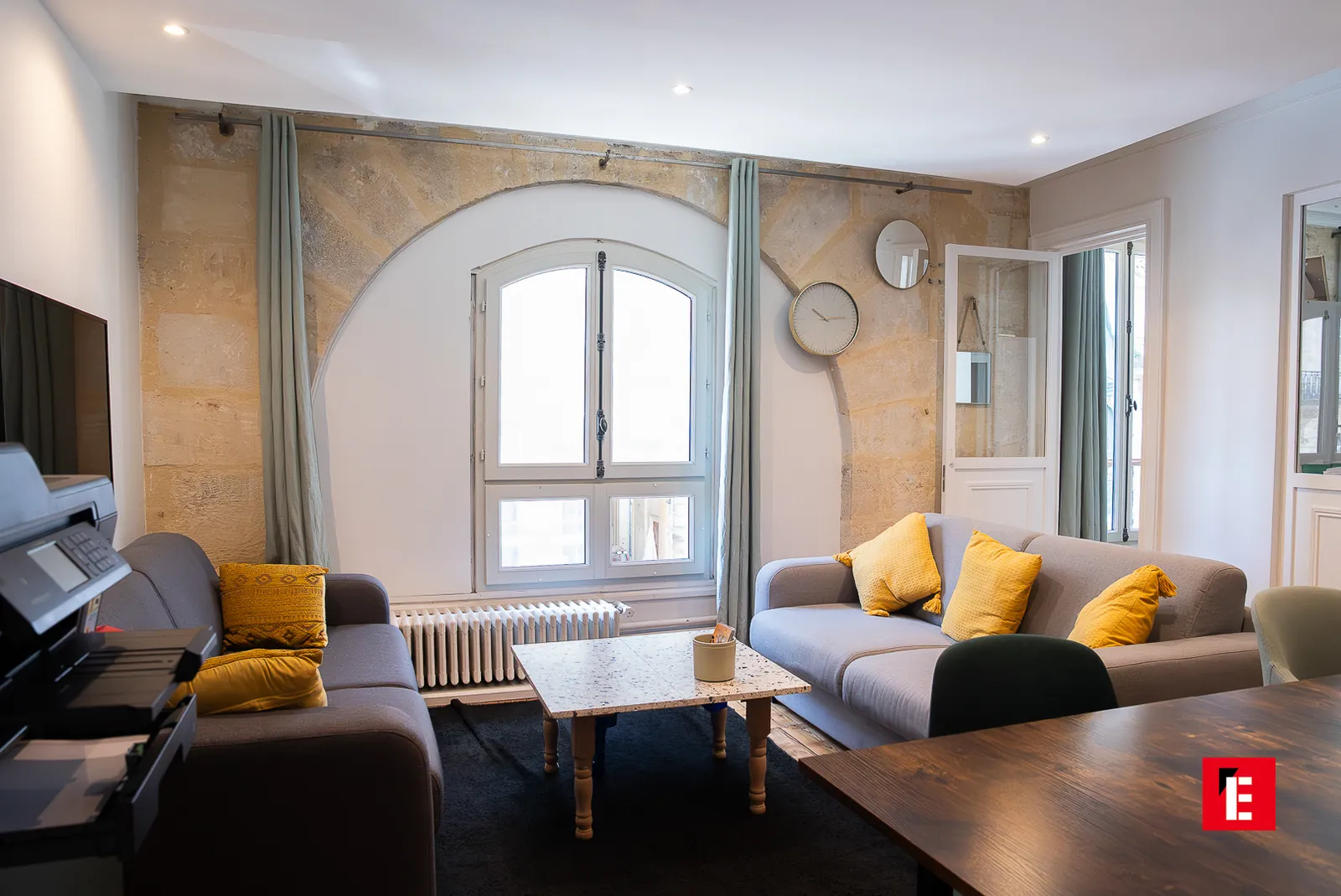 Coin salon avec canapés, coussins jaunes et arche de pierre près de la fenêtre — Bordeaux Esprit des Lois