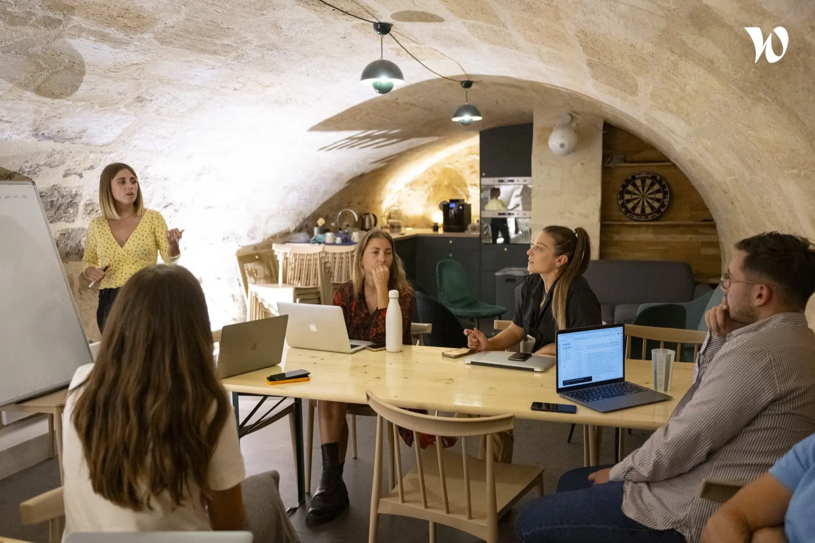 Session de travail dans la cave voûtée en pierre, tables en bois et suspensions — Bordeaux Leyteire
