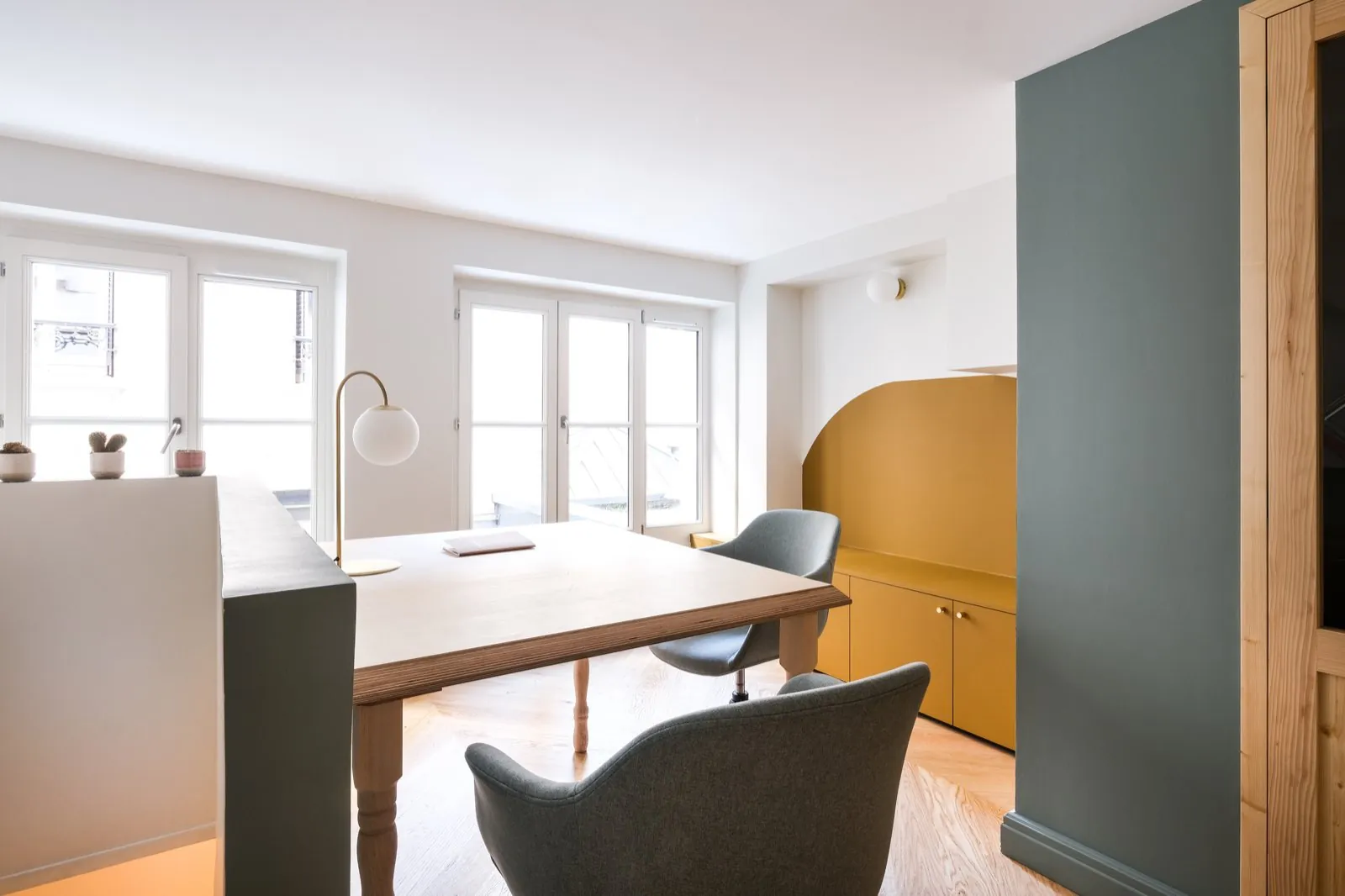 Bureau privatif lumineux : grande table en bois, fauteuils et banc moutarde près des fenêtres — Passage de Lyon